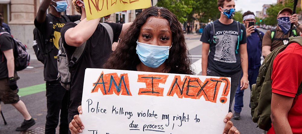 Black woman holds protest sign that says 