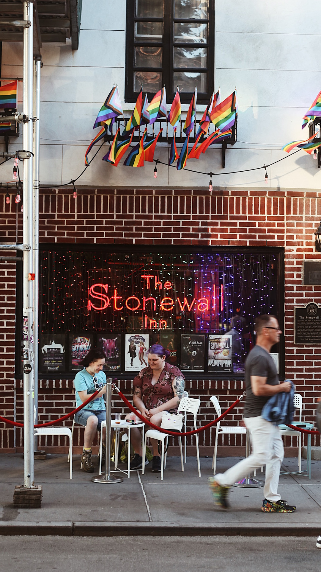Two people sit in front o the Stonewall Inn.