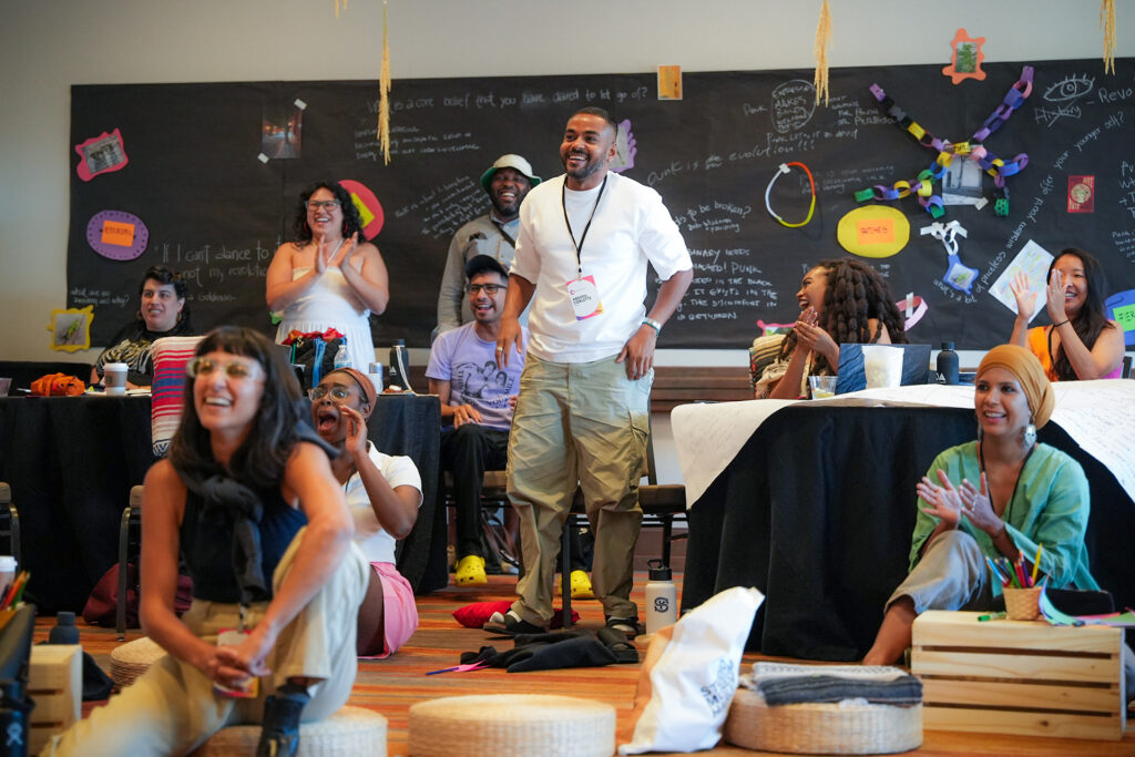 People laugh and applaud for presenters at 2024 Creative Change Retreat